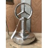 A CHROME MERCEDES SIGN ON A BASE