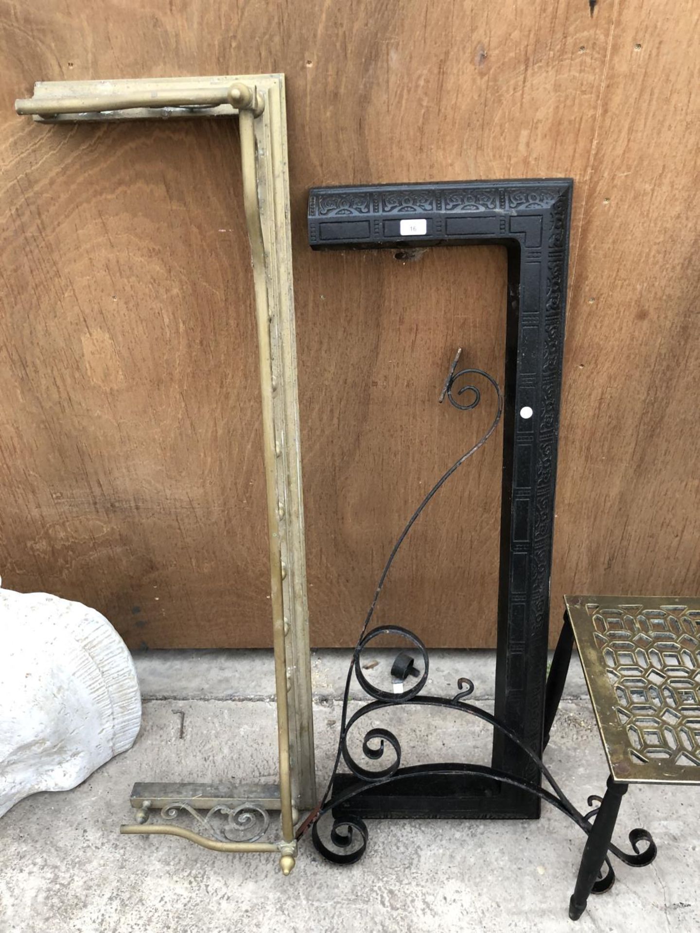 A BLACK FIRE FENDER AND AN ORNATE WROUGHT IRON SIGN BRACKET