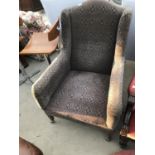 AN UPHOLSTERED WING BACK ARMCHAIR