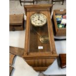 A VINTAGE OAK CASED CHIMING WALL CLOCK WITH PENDULUM