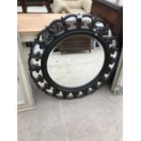 A ROUND MIRROR WITH BLACK AND GILDED FRAME