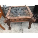 A CARVED INDONESIAN WOOD COFFEE TABLE WITH ORNATE METAL TOP