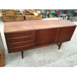 A TEAK LONG JOHN SIDEBOARD WITH FOUR DRAWERS AND TWO SLIDING DOORS
