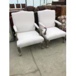 A PAIR OF LARGE CREAM UPHOLSTERED ARMCHAIRS WITH SILVER COLOURED METAL SUPPORTS