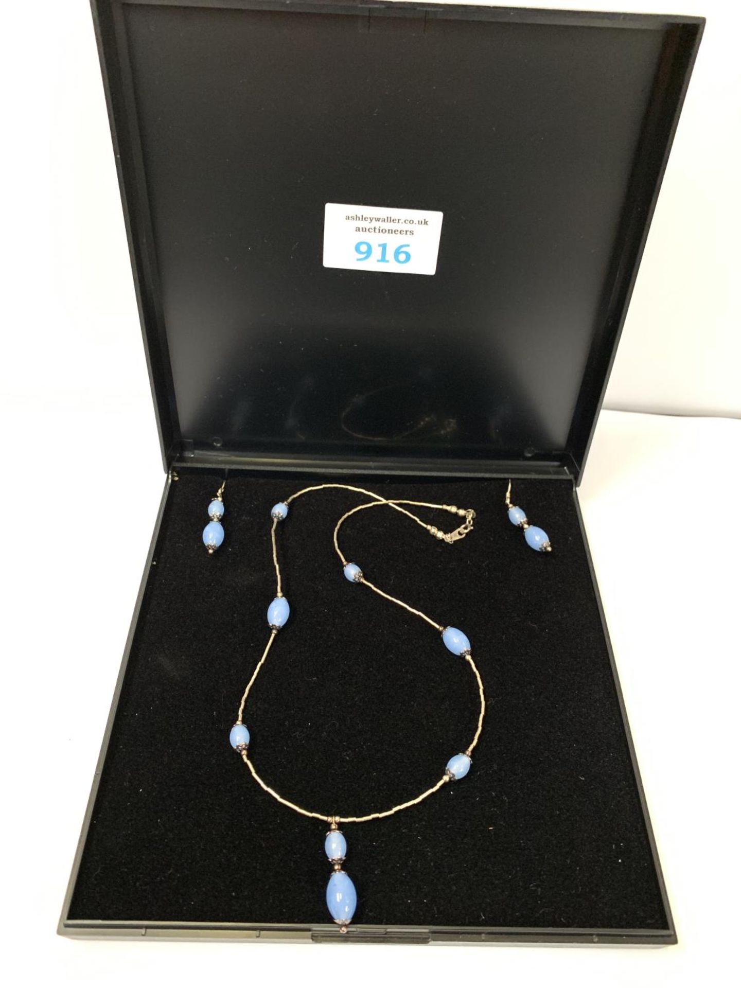 A BOXED SILVER NECKLACE AND EARRINGS SET WITH BLUE STONES