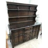 AN ERCOL ELM DRESSER WITH TWO DOORS FOUR DRAWERS AND UPPER SPLASHBACK