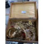 A WOODEN BOX CONTAINING YELLOW METAL COSTUME JEWELLERY