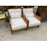 A PAIR OF TEAK AND RATTAN ARMCHAIRS WITH CREAM UPHOLSTERED CUSHIONS