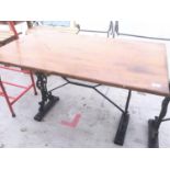 A RECTANGULAR WOODEN TOP TABLE ON A CAST IRON SUPPORT