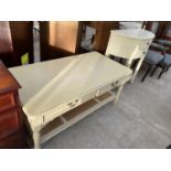 A CREAM COFFEE TABLE WITH TWO DRAWERS AND LOWER RATTAN SHELF AND A CREAM DEMI LUNE CABINET WITH