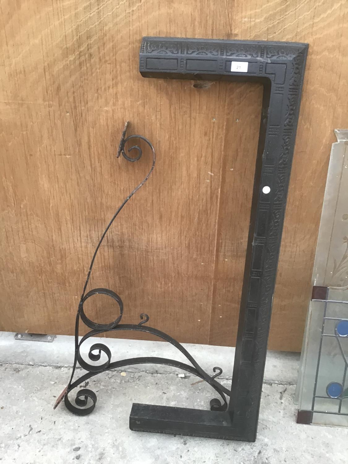 A BLACK FIRE FENDER AND AN ORNATE WROUGHT IRON SIGN BRACKET