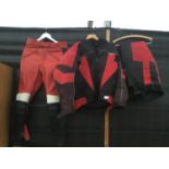A MOTORCYCLISTS WATER PROOF JACKET AND TROUSERS AND A PAIR OF RED BLACK AND WHITE LEATHER TROUSERS
