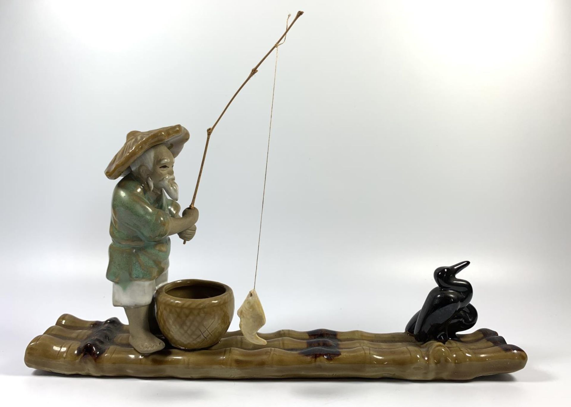 A CHINESE STONEWARE MODEL OF A FISHERMAN ON BAMBOO RAFT, HEIGHT 18CM