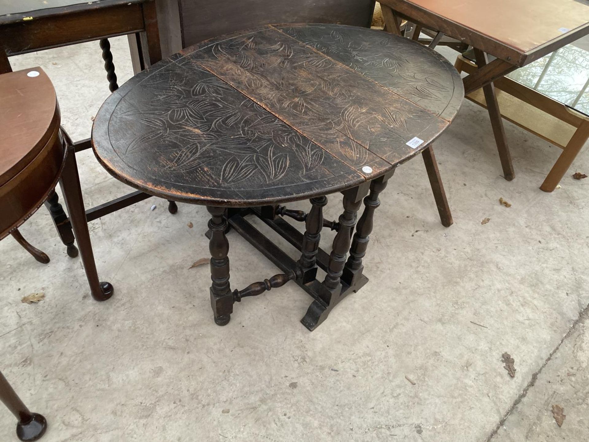 AN OVAL OAK DROP LEAF SIDE TABLE WITH CARVED TOP