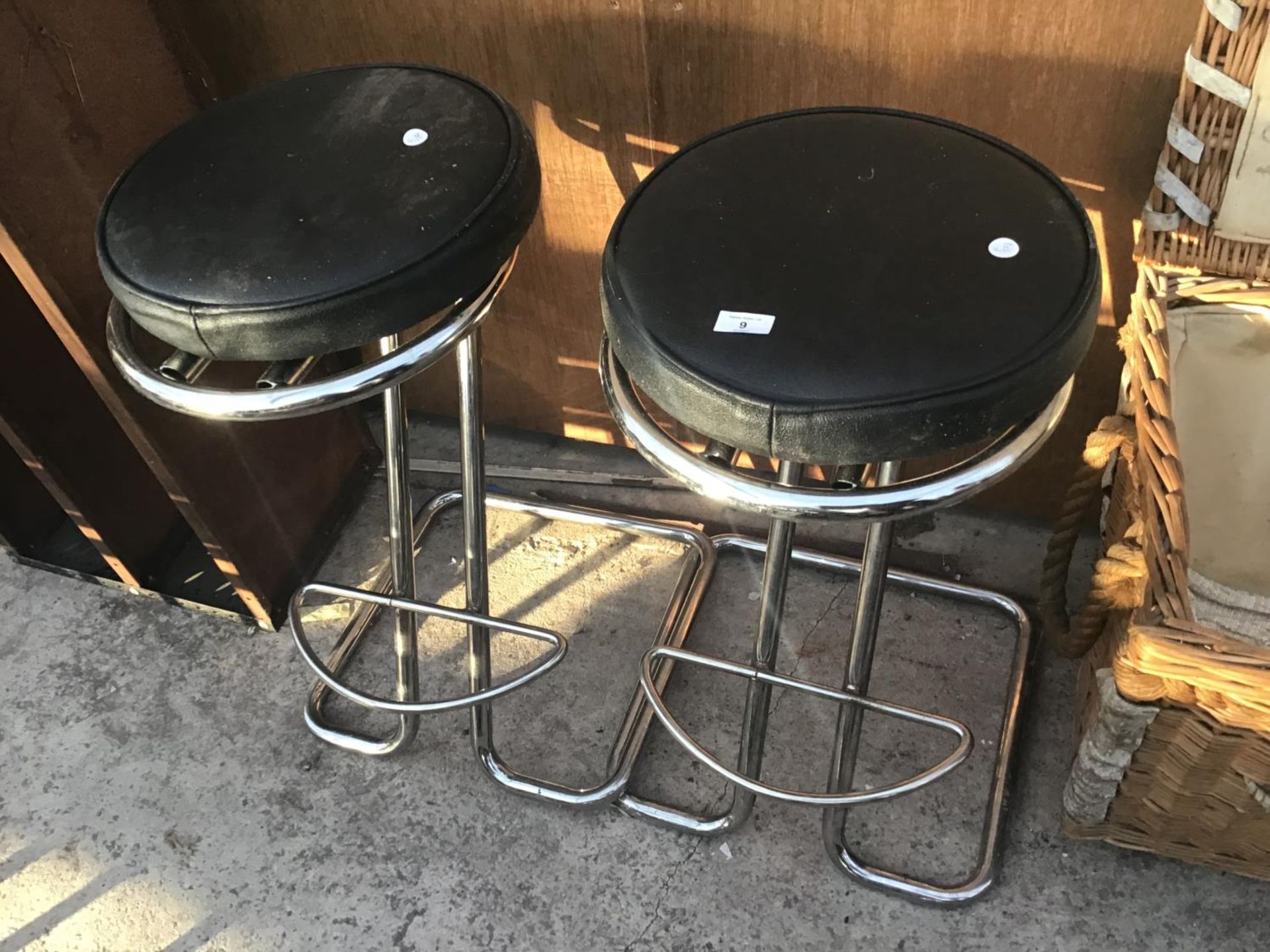 A PAIR OF CHROME FRAMED BAR STOOLS WITH BLACK LEATHERETTE SEATS