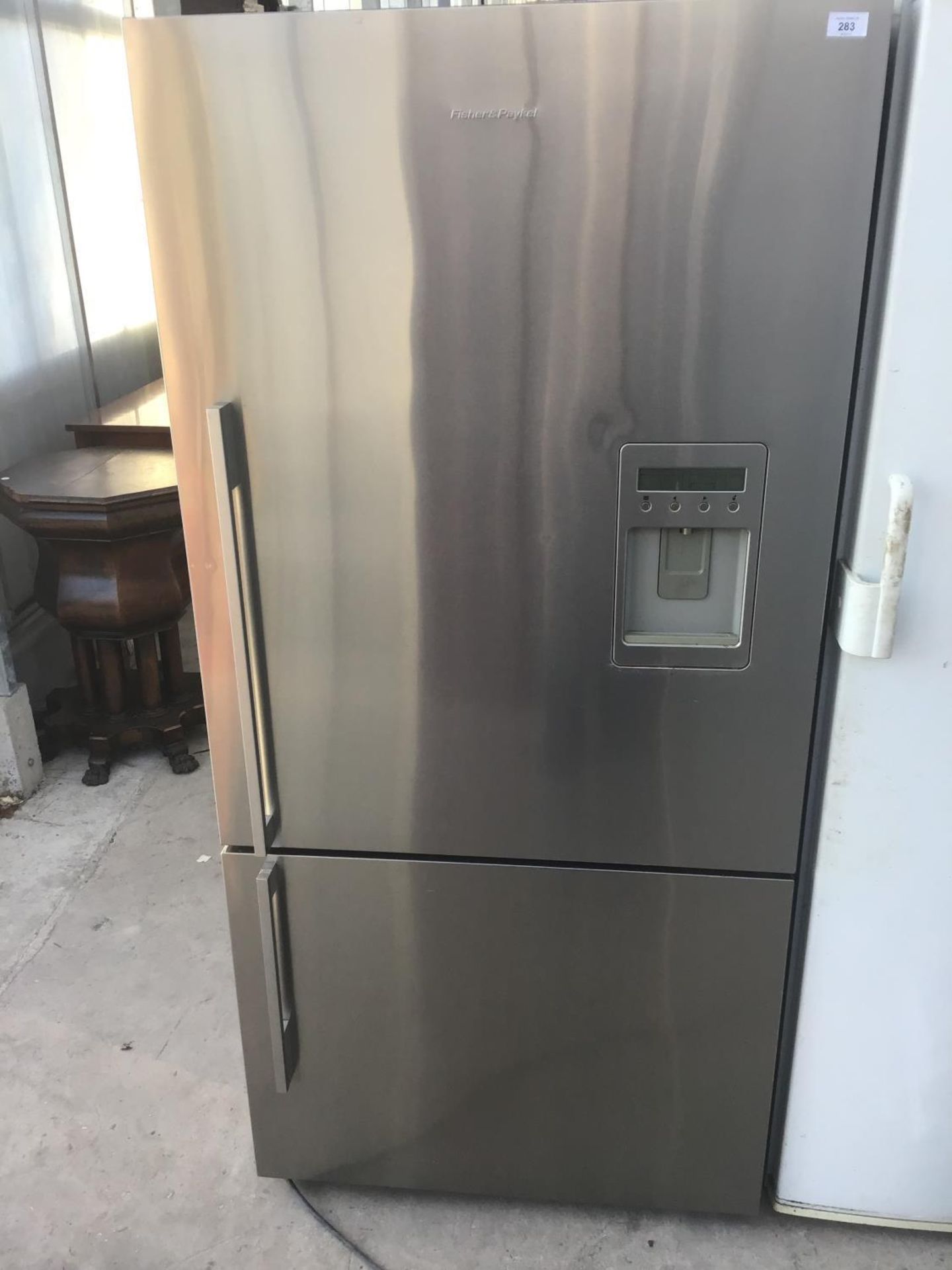 A FISHER AND PAYKEL SILVER FRIDGE FREEZER WITH WATER DISPENSER IN CLEAN AND WORKING ORDER