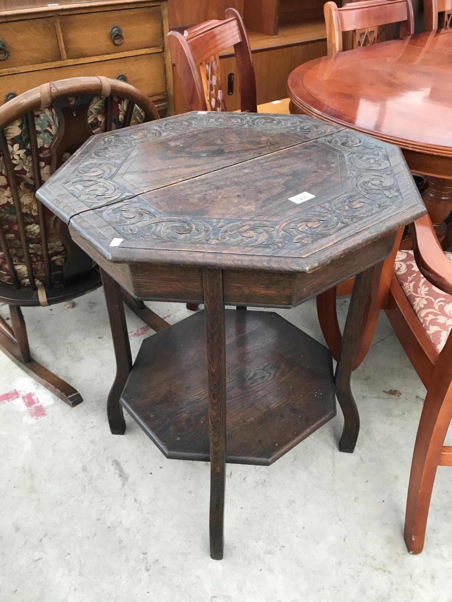 AN OCTAGONAL OAK OCCASIONAL TABLE WITH CARVED TOP AND LOWER SHELF