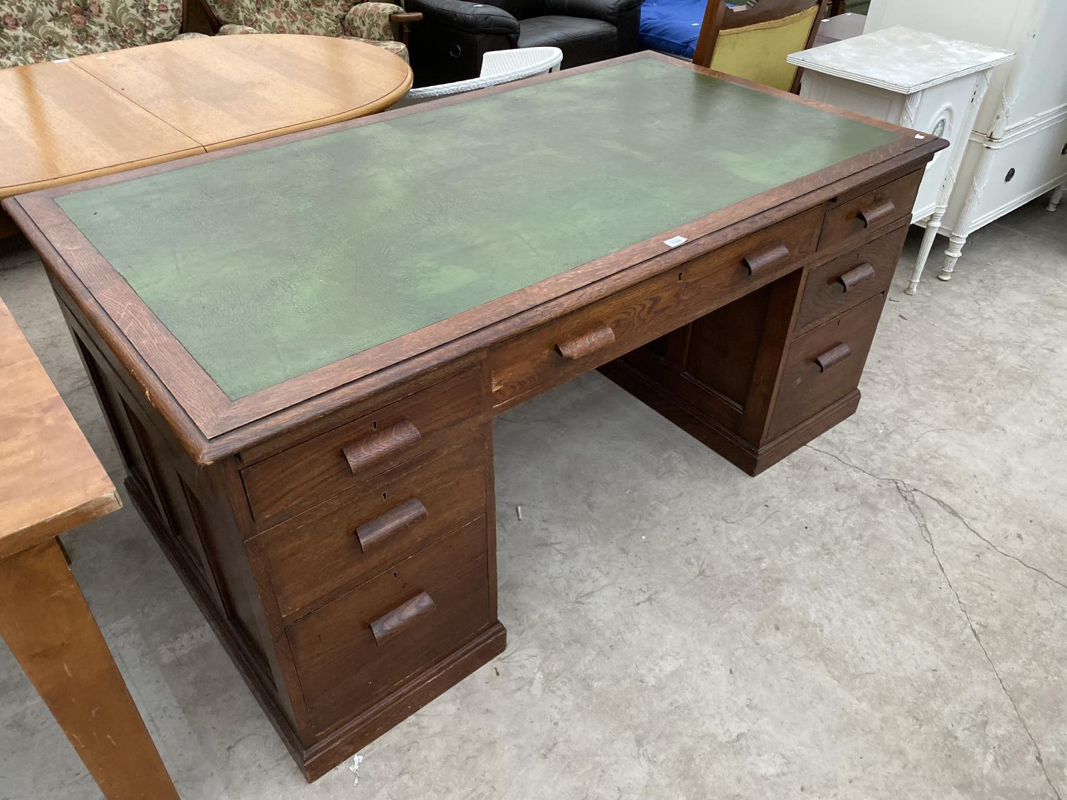 AN OAK TWIN PEDESTAL DESK WITH GREEN LEATHER WRITING SURFACE AND SEVEN DRAWERS