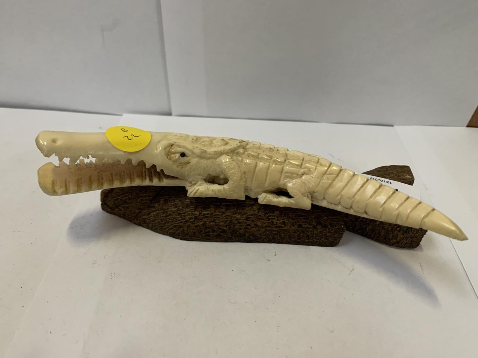 A BONE STYLE CROCODILE ON WOODEN BASE