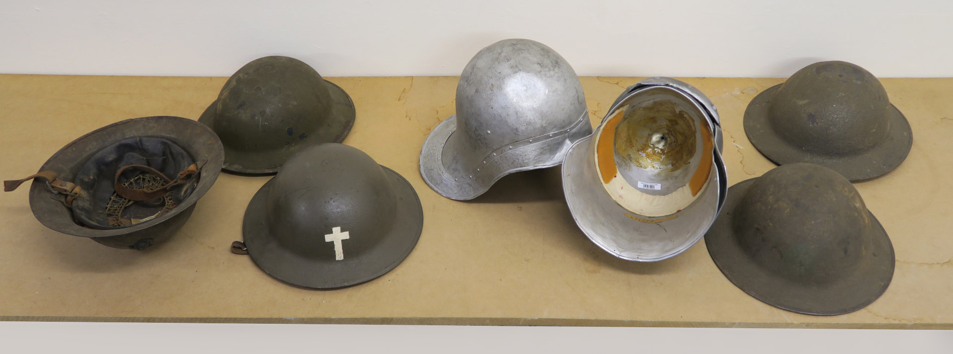 A collection of metal helmets with five being of a military style,
