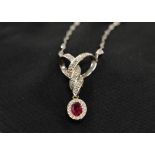 A ruby & diamond pendant H/M 14ct, suspended by a 9ct H/M chain, the oval pigeon blood red ruby