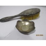 A small silver in dish along with a silver backed hair brush