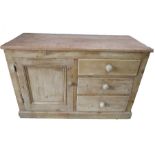 An antique pine dresser base with cupboard and three drawers