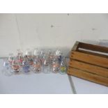 A collection of 20 various milk bottles with advertising labels, in wooden crate