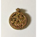 A gold coloured Oriental pendant set with Cabochon rubies. Total weight 7.2g