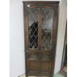 An oak corner cupboard with leaded light glazed doors