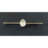 A 9ct gold bar brooch set with a single clear stone.