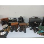 A collection of various binoculars and camera equipment including Polaroid camera, Skybolt