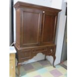 A mahogany cupboard on three drawers base with cabriole legs