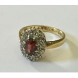 An 18ct gold ring with garnet and diamond surround.