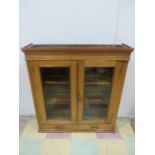 A pine cupboard with glazed doors and two drawers under - key in office