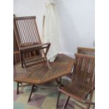 A teak garden table, six folding chairs, parasol and cast iron base