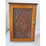 An oak and stained pine hanging cupboard with carved door