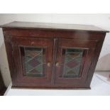 A small stained pine cabinet with stained glass panels