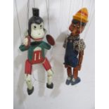 Two wooden marionette puppets, Pinocchio and a monkey playing the cymbals