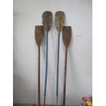 A vintage pair of wooden oars along with a pair of padddles