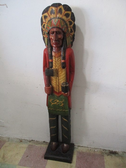 A carved wooden tobacco store Native American in traditional dress with detachable tomahawk,