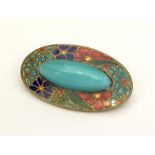 An enamelled brooch set with a cabochon stone.