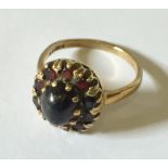 A 9ct gold garnet cluster ring with cabochon stone to the centre.