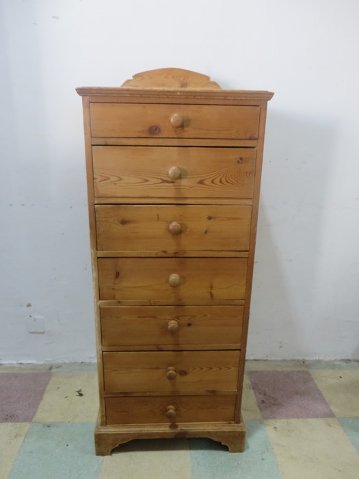 A narrow pine chest of seven drawers