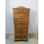 A narrow pine chest of seven drawers