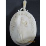 A carved ivory pendant circa 1910 decorated with a Classical scene