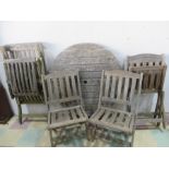 A round teak garden table and four chairs along with a teak steamer chair