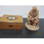 A terracotta figure of a fisherman mending his nets along with a wooden box
