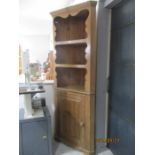 A stained pine corner cupboard with shelves over