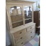 An antique pine dresser with glazed doors and four drawers under